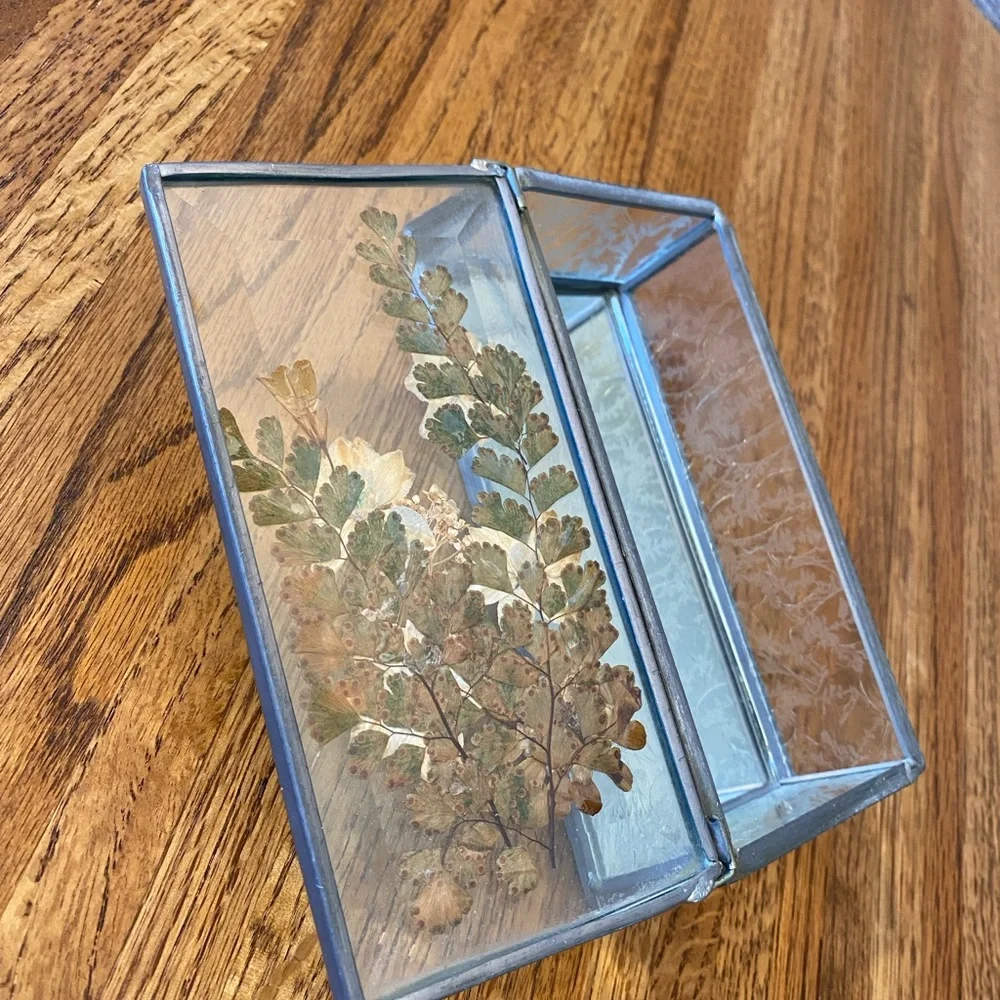 Small, heavy glass box with pressed flowers on top and mirrored bottom